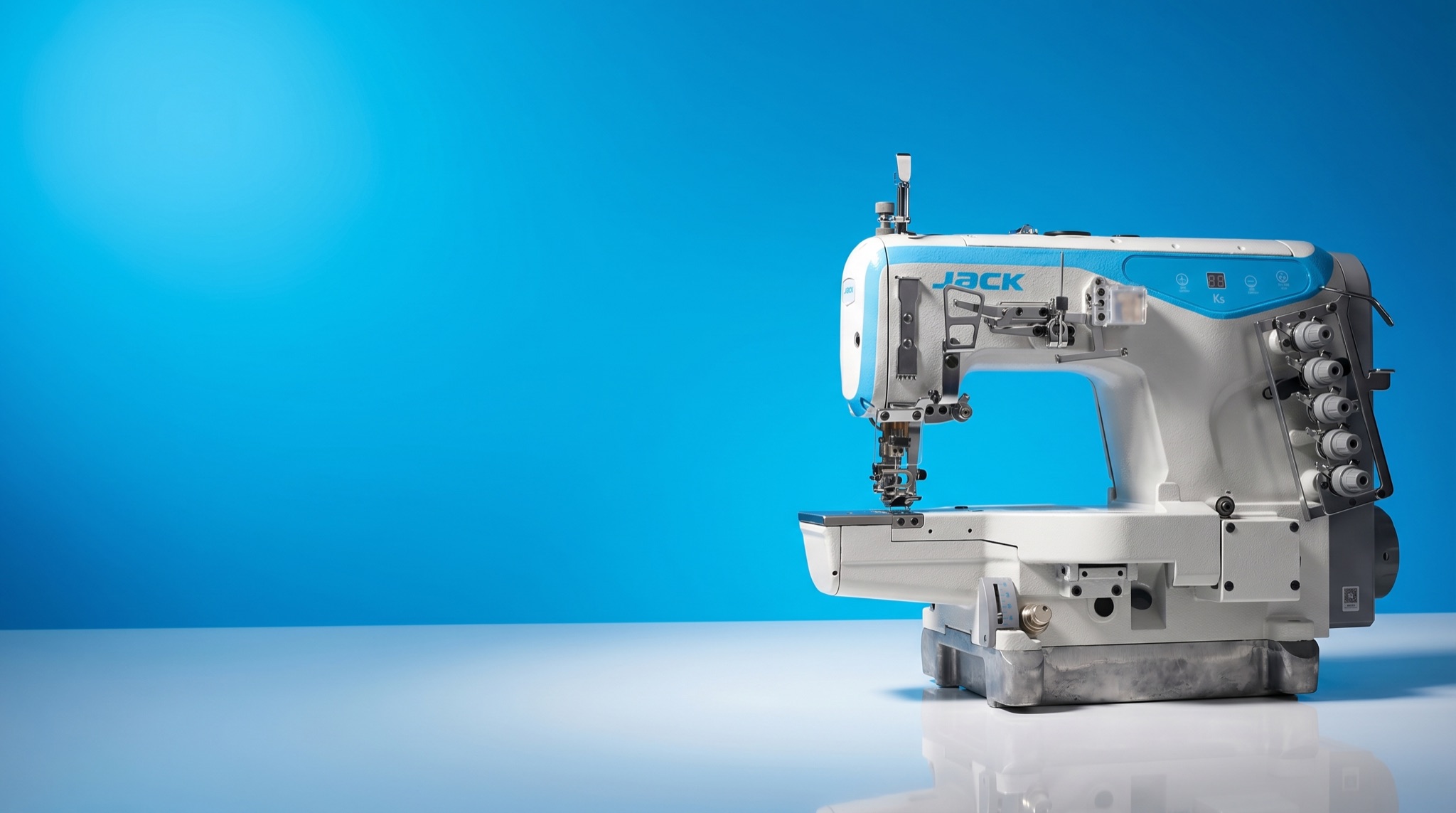 Jack K5 cylinder-bed coverstitch industrial sewing machine on a vivid azure studio panel